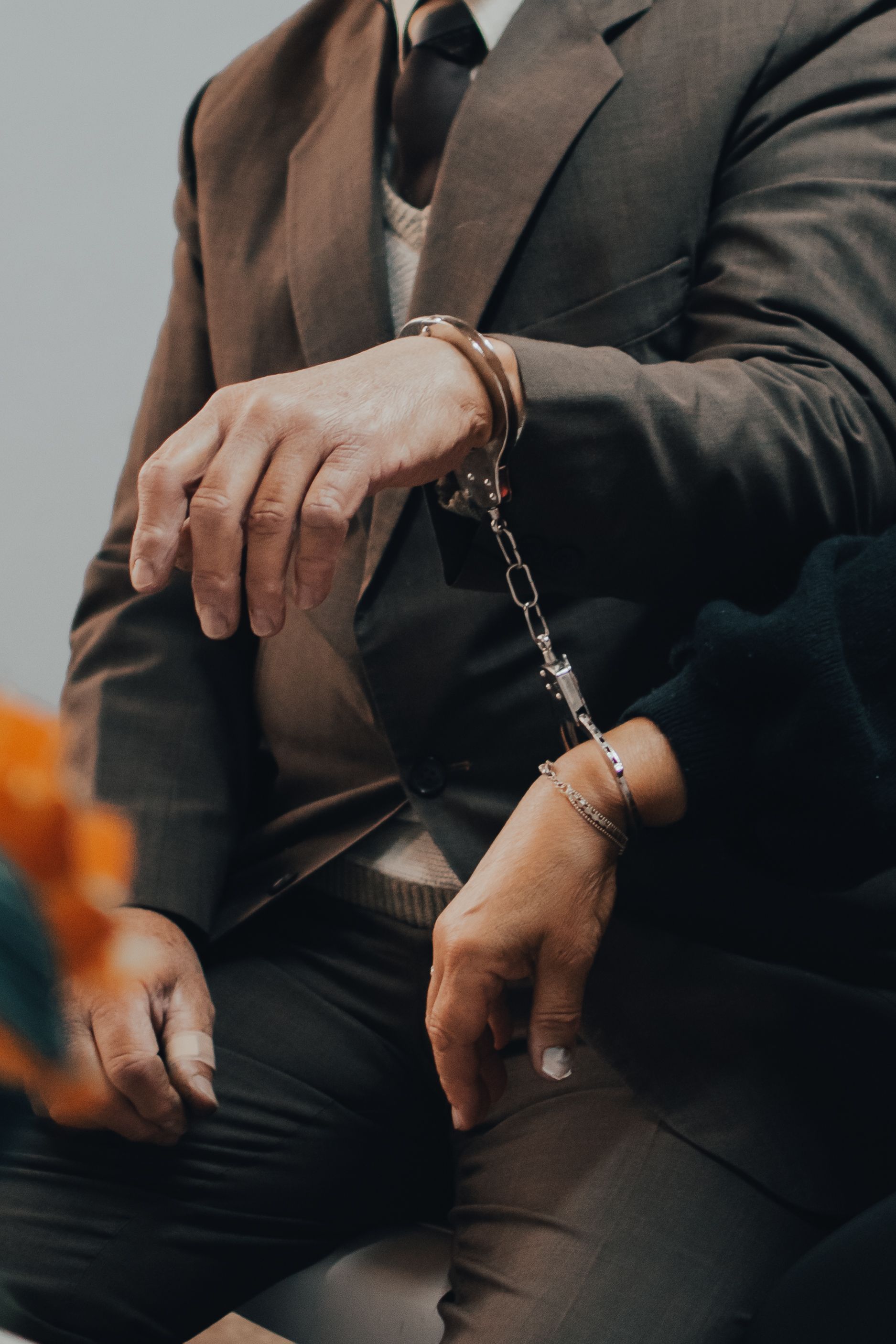 Close-up of two individuals in suits handcuffed together during a serious meeting.